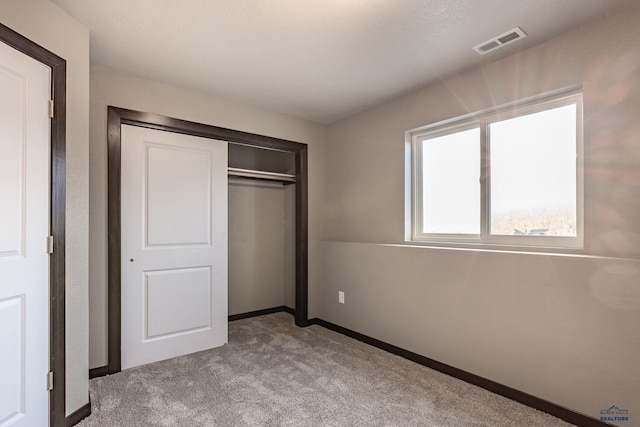 unfurnished bedroom with a closet and light carpet