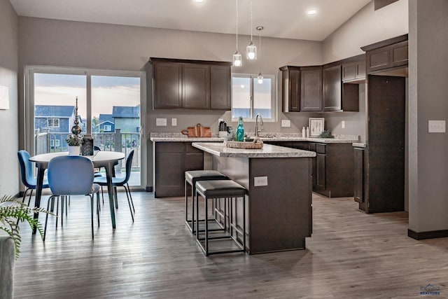 kitchen with decorative light fixtures, a kitchen breakfast bar, hardwood / wood-style floors, and a kitchen island