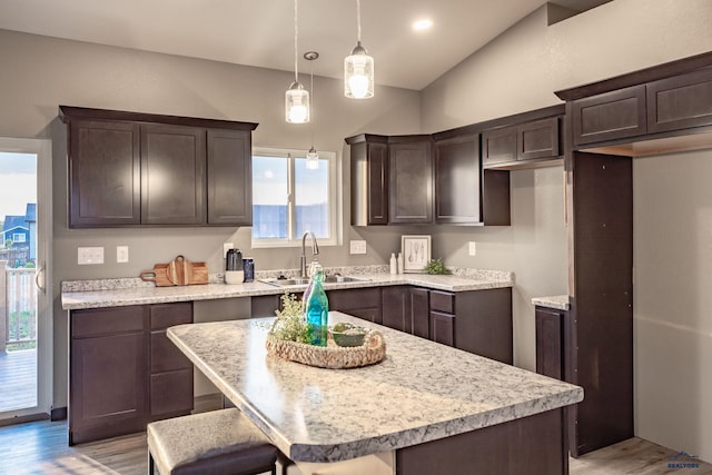 kitchen featuring a kitchen island, pendant lighting, dark brown cabinetry, and sink