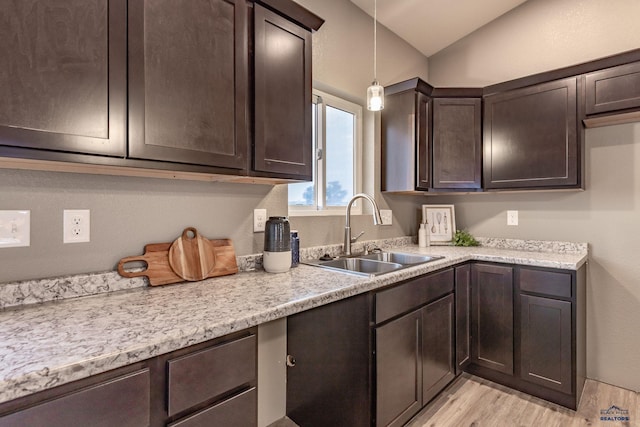 kitchen featuring vaulted ceiling, dark brown cabinets, hanging light fixtures, and sink