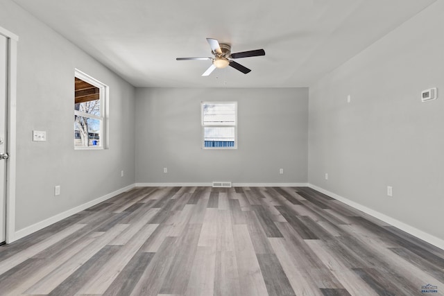 empty room with ceiling fan, a wealth of natural light, and hardwood / wood-style floors