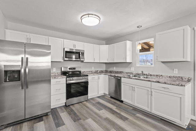 kitchen featuring decorative light fixtures, appliances with stainless steel finishes, sink, and white cabinetry