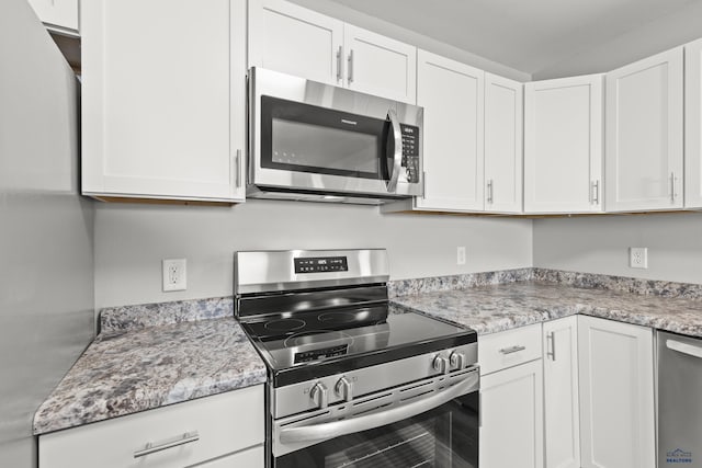 kitchen featuring stainless steel appliances, white cabinets, and light stone countertops