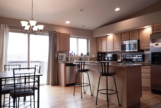 kitchen featuring an inviting chandelier, appliances with stainless steel finishes, hanging light fixtures, and dark stone counters