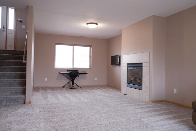 unfurnished living room featuring light colored carpet and a tile fireplace