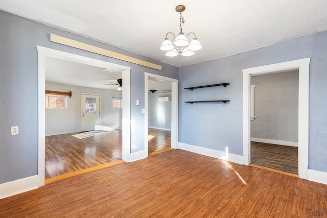 spare room with a textured ceiling, ceiling fan with notable chandelier, and wood-type flooring