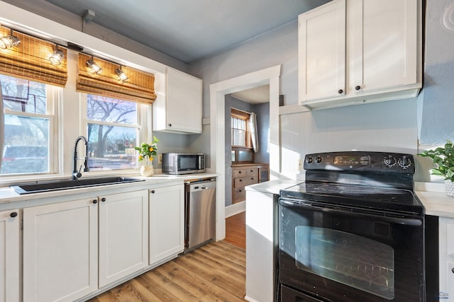 kitchen featuring appliances with stainless steel finishes, light hardwood / wood-style floors, white cabinetry, and sink