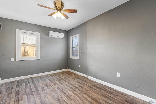 unfurnished room with ceiling fan, an AC wall unit, and light wood-type flooring