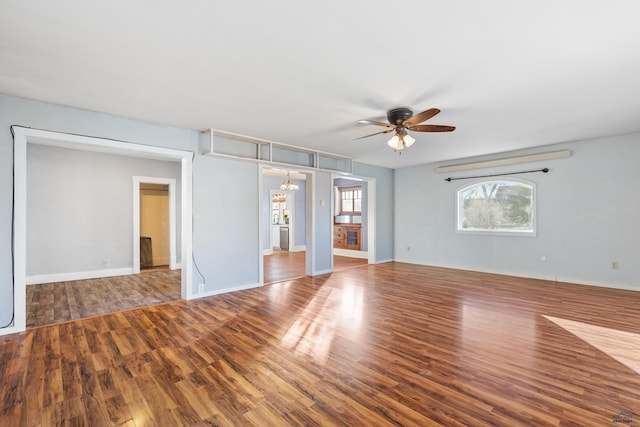 interior space with ceiling fan with notable chandelier and hardwood / wood-style flooring