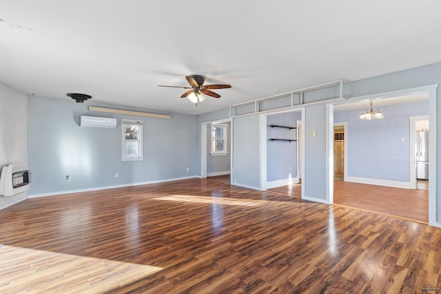 spare room featuring heating unit, a wall mounted AC, ceiling fan with notable chandelier, and wood-type flooring