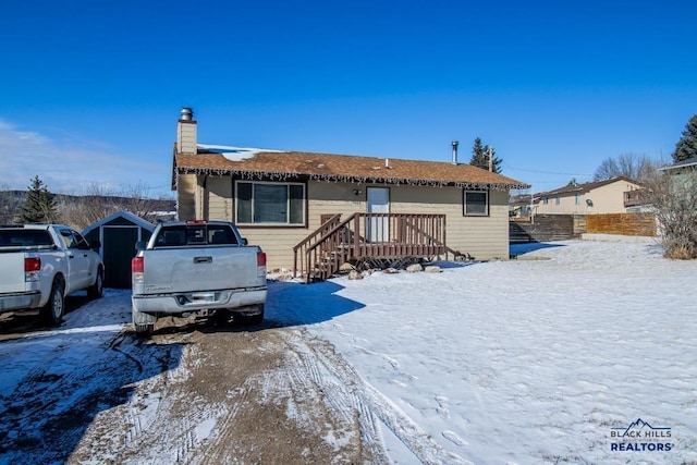 snow covered rear of property with a deck