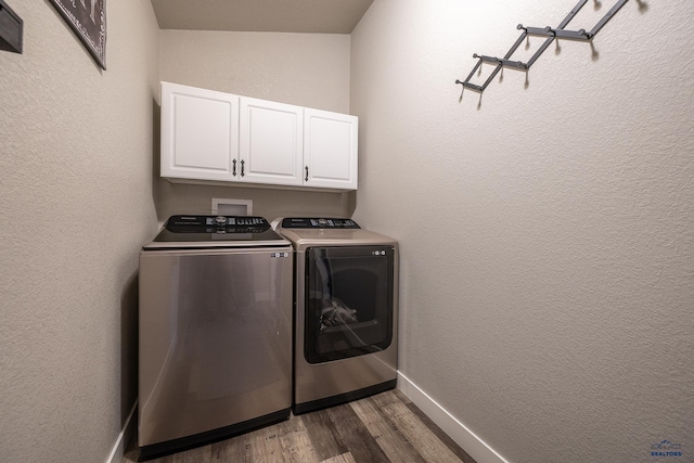 laundry area featuring washing machine and dryer, dark hardwood / wood-style floors, and cabinets