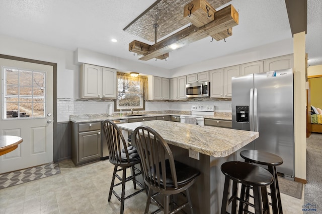 kitchen featuring a center island, stainless steel appliances, sink, a breakfast bar, and gray cabinetry