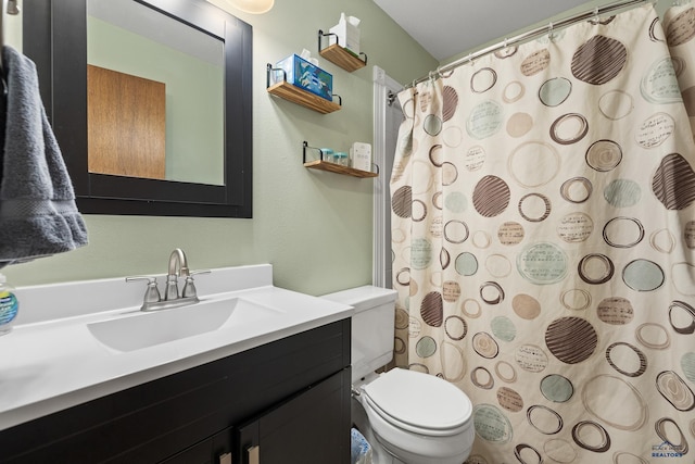 bathroom featuring toilet, vanity, and curtained shower