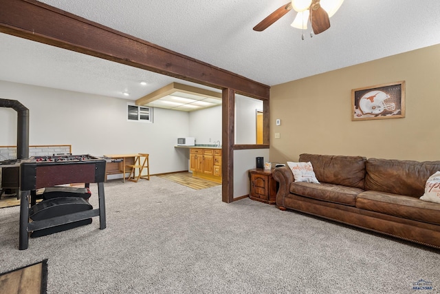 carpeted living room with beam ceiling, ceiling fan, and a textured ceiling