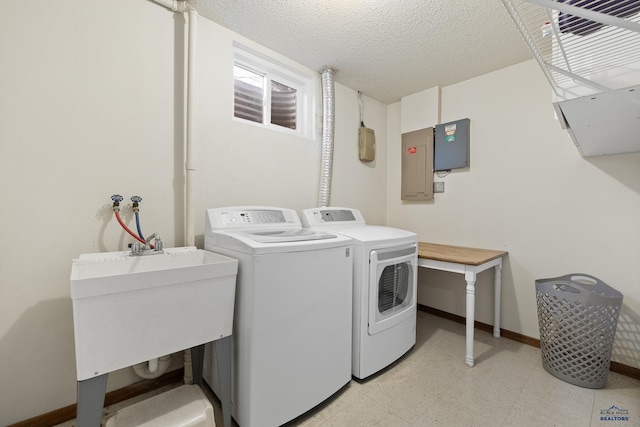 laundry area with a textured ceiling, electric panel, washing machine and clothes dryer, and sink