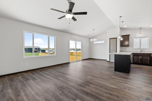 unfurnished living room featuring vaulted ceiling, dark wood-type flooring, ceiling fan with notable chandelier, and sink