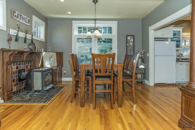 dining space with a chandelier, a wood stove, and light hardwood / wood-style flooring