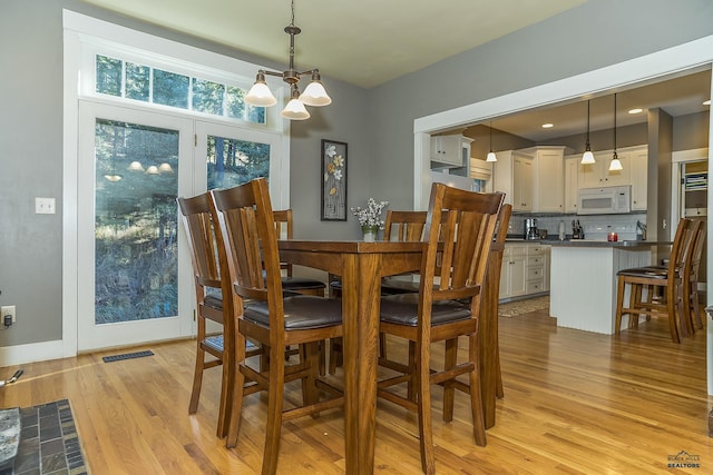 dining space featuring light wood-type flooring and an inviting chandelier