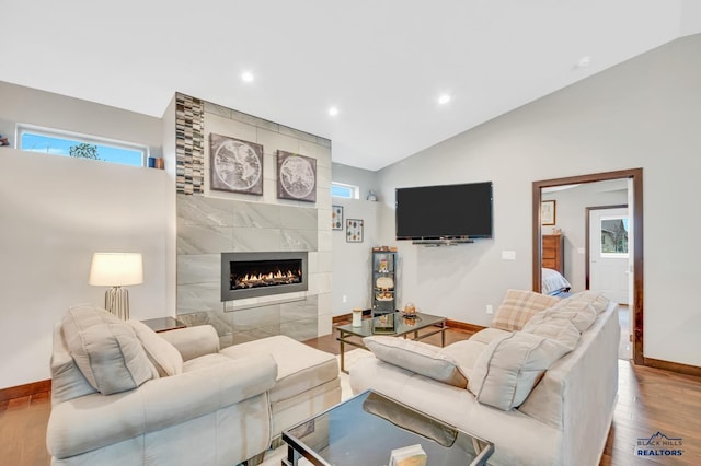 living room featuring vaulted ceiling, a fireplace, and light hardwood / wood-style flooring