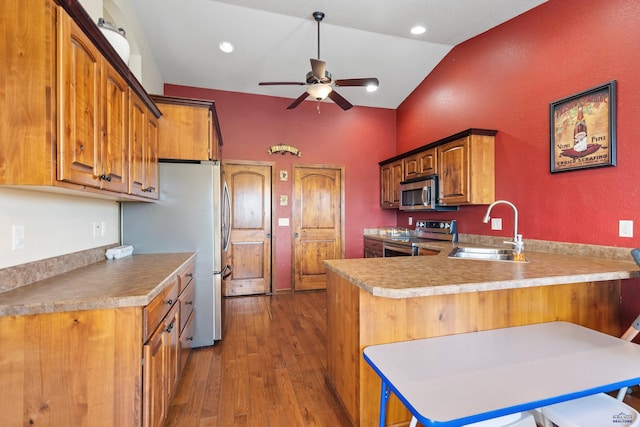 kitchen with lofted ceiling, sink, appliances with stainless steel finishes, a kitchen breakfast bar, and kitchen peninsula