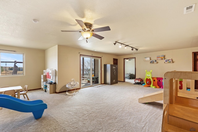 playroom with ceiling fan, light colored carpet, and a textured ceiling