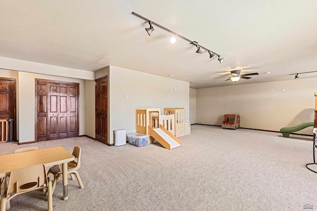 playroom featuring light carpet, ceiling fan, and a textured ceiling