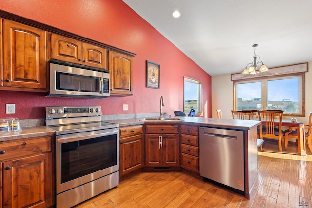 kitchen featuring lofted ceiling, sink, pendant lighting, light hardwood / wood-style flooring, and stainless steel appliances