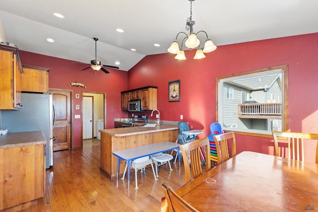 kitchen featuring sink, appliances with stainless steel finishes, washing machine and clothes dryer, decorative light fixtures, and kitchen peninsula