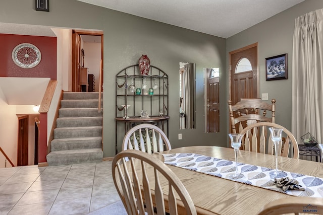 dining room featuring a textured ceiling, light tile patterned floors, and lofted ceiling