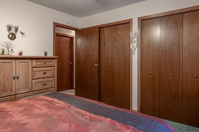 unfurnished bedroom featuring a textured ceiling, multiple closets, and carpet floors