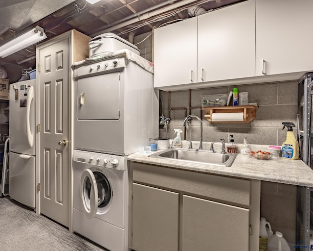 laundry area featuring stacked washer and clothes dryer and sink