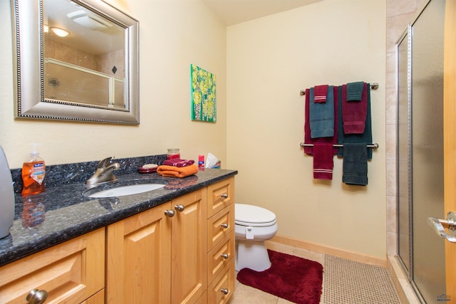 bathroom featuring vanity, toilet, a shower with door, and tile patterned flooring