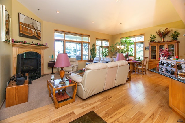 living room featuring vaulted ceiling, a wealth of natural light, a high end fireplace, and light hardwood / wood-style floors