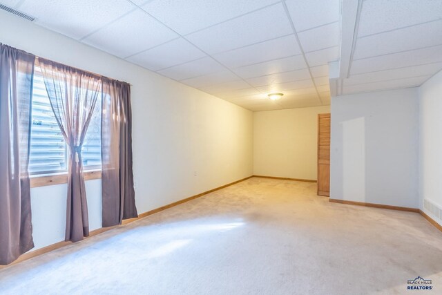 empty room featuring a paneled ceiling and light carpet