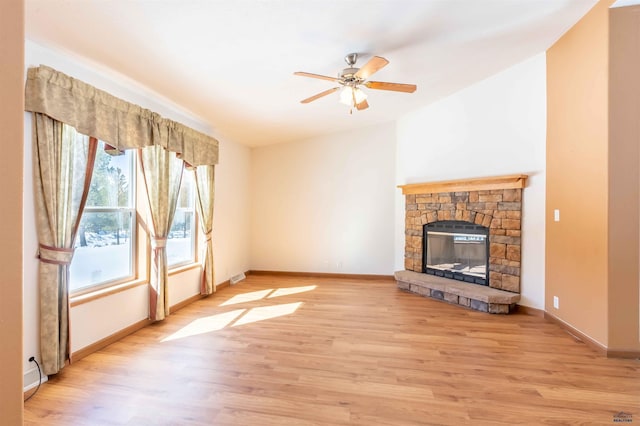 unfurnished living room with light wood-type flooring, ceiling fan, and a stone fireplace