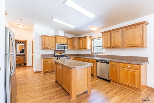 kitchen with a center island, appliances with stainless steel finishes, light wood-type flooring, sink, and vaulted ceiling