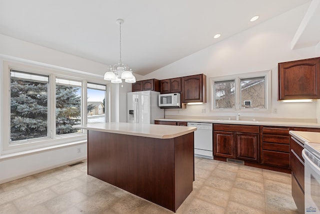 kitchen featuring a center island, white appliances, sink, pendant lighting, and lofted ceiling