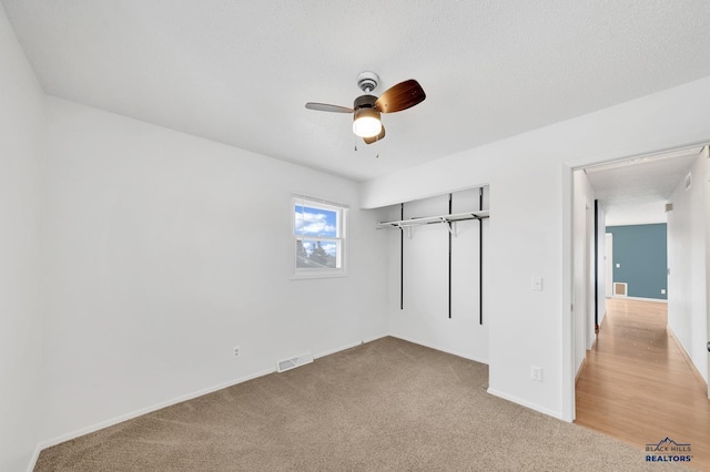 unfurnished bedroom with a closet, ceiling fan, and light carpet