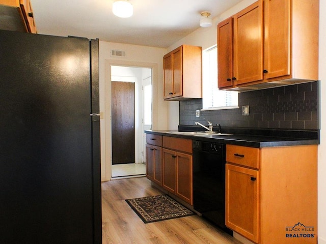 kitchen featuring black appliances, light wood-type flooring, decorative backsplash, and sink