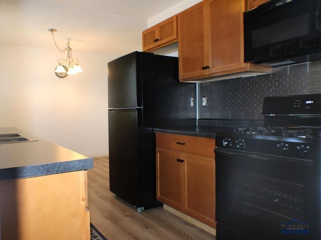 kitchen with black appliances, decorative light fixtures, light hardwood / wood-style floors, decorative backsplash, and sink