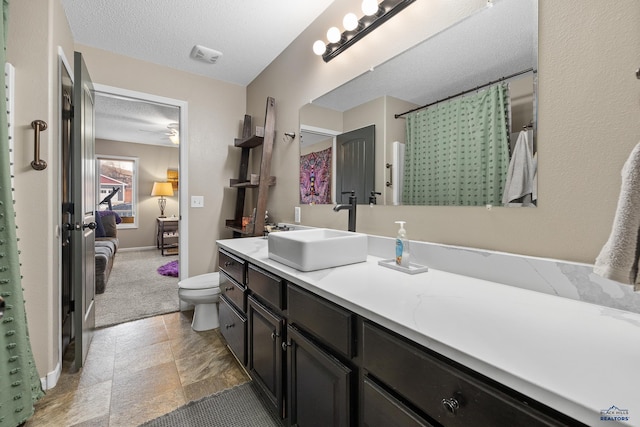 bathroom with vanity, toilet, and a textured ceiling