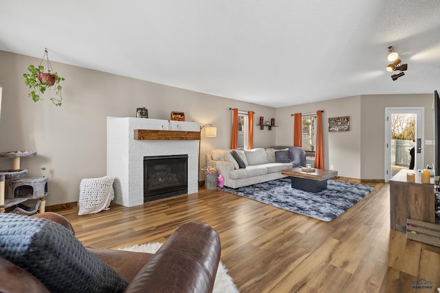 living room with hardwood / wood-style flooring, a textured ceiling, and a fireplace