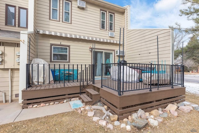 rear view of house with a swimming pool side deck and a wall unit AC