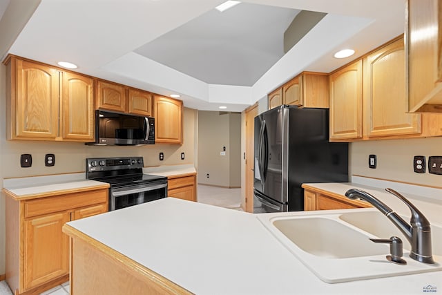 kitchen with sink, a tray ceiling, light tile patterned floors, and appliances with stainless steel finishes