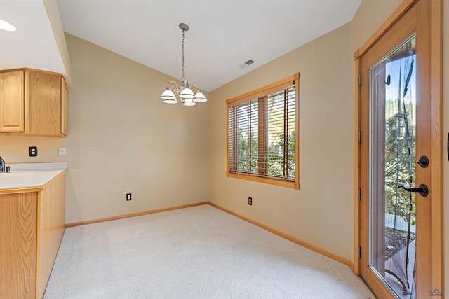 interior space featuring vaulted ceiling, decorative light fixtures, light brown cabinets, a notable chandelier, and light carpet