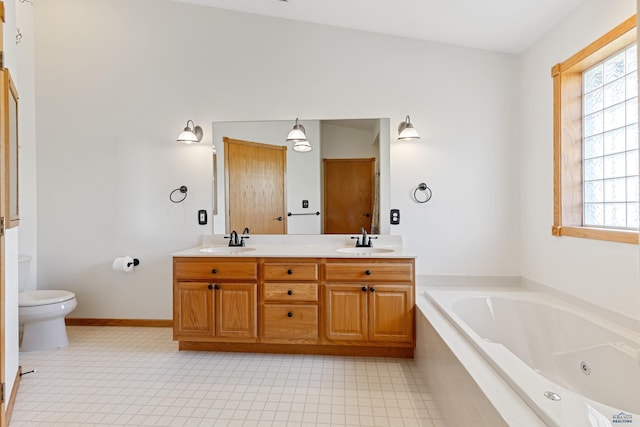 bathroom featuring vanity, a relaxing tiled tub, and toilet