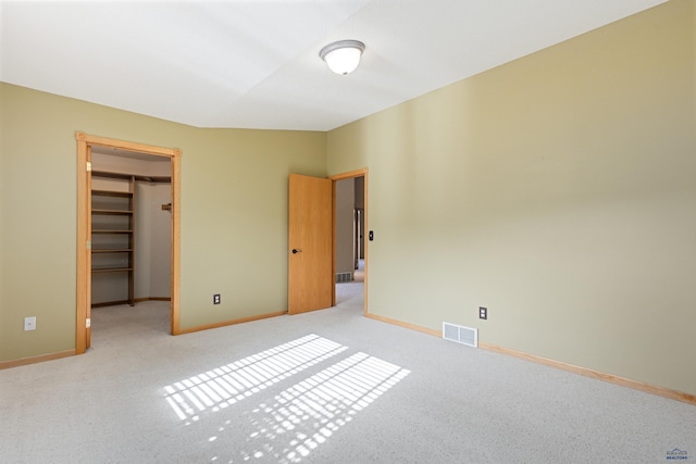 unfurnished bedroom with a walk in closet, light carpet, and a closet