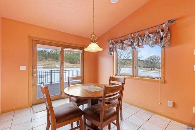 dining area with light tile patterned floors and vaulted ceiling