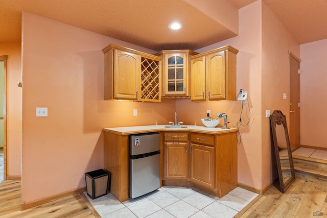 kitchen featuring sink, stainless steel fridge, and light wood-type flooring